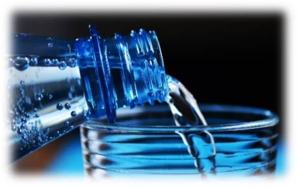 close up water pouring from a bottle into a glass